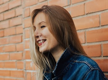 Woman Wearing Blue Denim Jacket Leaning on Brick Wall