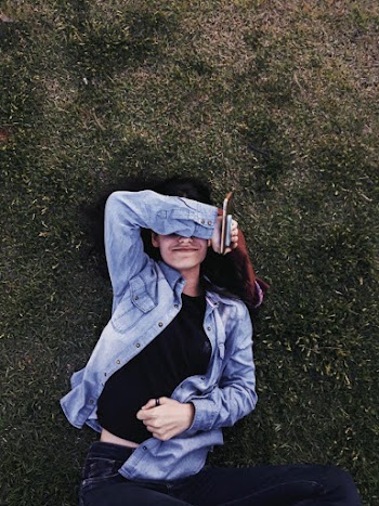Woman Wearing Blue Denim Jacket Lying on Green Grass