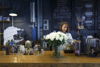 Woman Wearing Blue Denim Jacket Near White Flower on Table