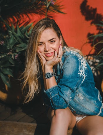 Woman Wearing Blue Denim Jacket Sitting Near Red Surface
