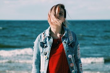 woman wearing blue denim jacket standing near body of water