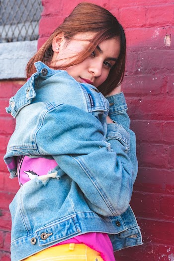 Woman Wearing Blue Denim Jacket Standing Near Red Wall