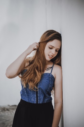 Woman Wearing Blue Denim Tank Top Leaning On White Wall