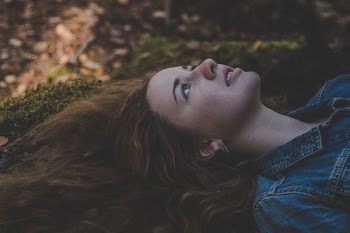 woman wearing blue denim top laying on green grass