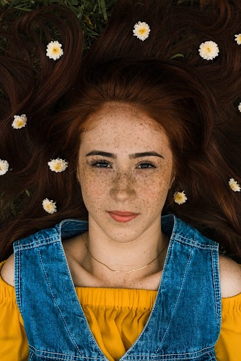 Woman Wearing Blue Denim Vest With White and Yellow Flowers on Hair Smiling