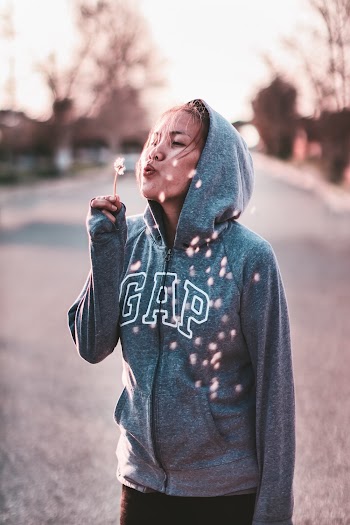 Woman Wearing Blue Gap Jacket While Blowing Flower