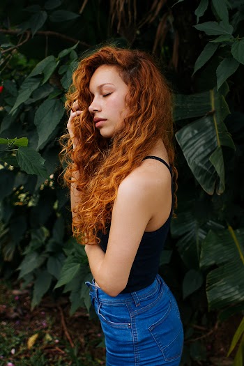 woman wearing blue  jeans and a sleeveless top with eyes closed