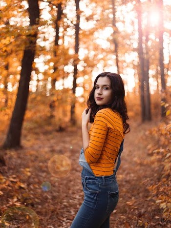 woman wearing blue jeans standing under brown trees