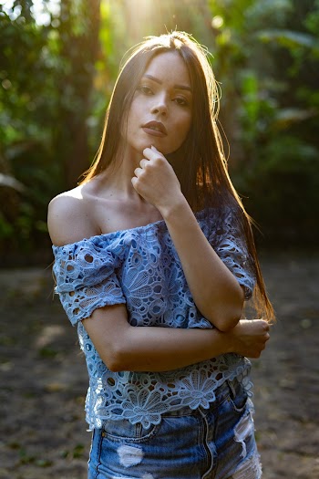 Woman Wearing Blue Lace Off-shoulder Blouse Standing While Touching Her Chin