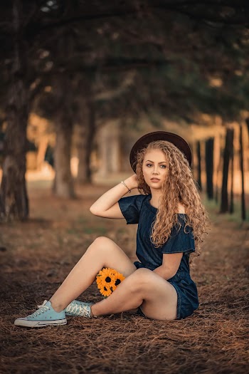 Woman Wearing Blue Off-shoulder Romper Sitting on Ground Holding Orange Flowers
