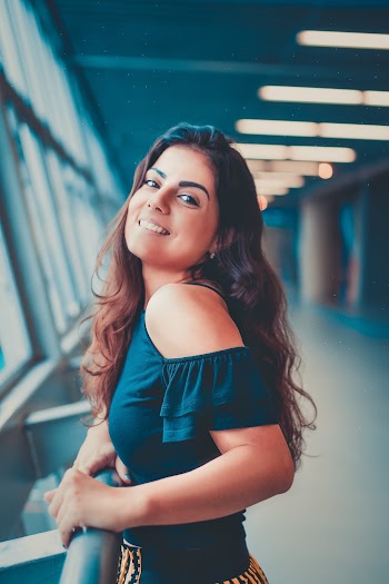 Woman Wearing Blue Offshoulder Top Holding on Gray Steel Rail