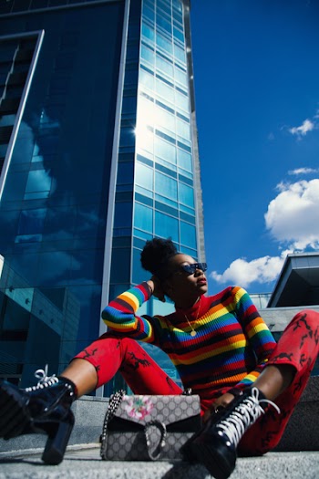 Woman Wearing Blue, Red, and Black Turtle-neck Long-sleeved Shirt and Red Pants Sitting on Ground at Daytime