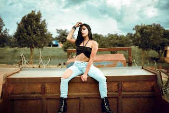 Woman Wearing Blue Ripped Jeans Sitting on Brown Dump Truck Top