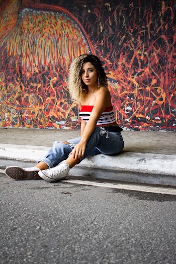 Woman Wearing Blue Ripped Jeans Sitting on Gray Concrete Pavement