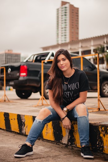 Woman Wearing Blue Ripped Jeans Sitting On Pavement