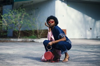 Woman Wearing Blue Shirt and Pants Holding Red Leather Barrel Bag
