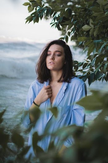 woman wearing blue top beside body of water at daytime