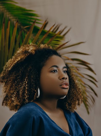 Woman Wearing Blue Top With Brown Curly Hair