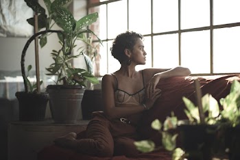 Woman Wearing Bra Leaning on Sofa Looking Outside the Window