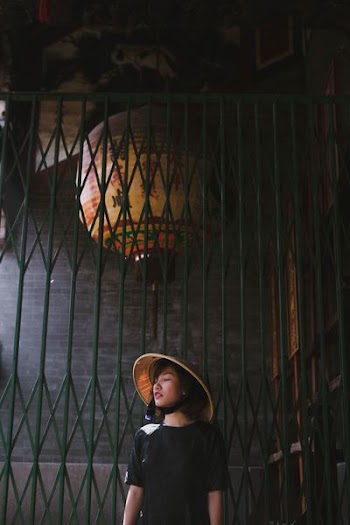 woman wearing brown bamboo hat standing near metal gate