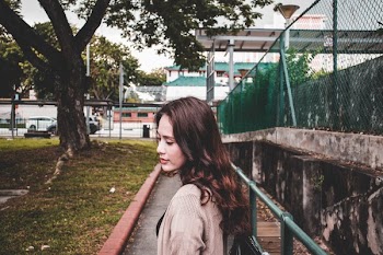 Woman Wearing Brown Cardigan Walking on Park Near a Green Tree