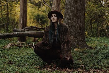 woman wearing brown coat sitting under tree