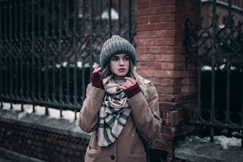 woman wearing brown coat standing beside of a black steel fence