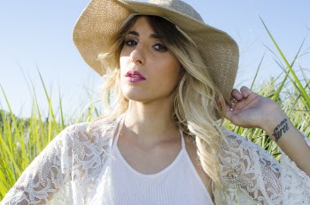 Woman Wearing Brown Hat and White Cardigan Standing in Middle of Grass Field