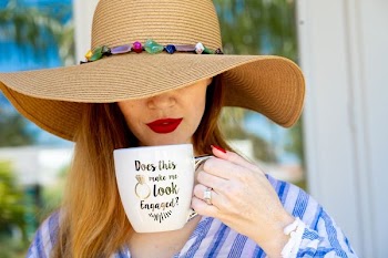 woman wearing brown hat holding white mug