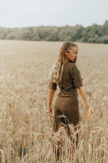 woman wearing brown outfit standing on brown grass field
