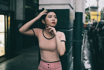 Woman Wearing Brown Shirt Leaning On A Building Wall