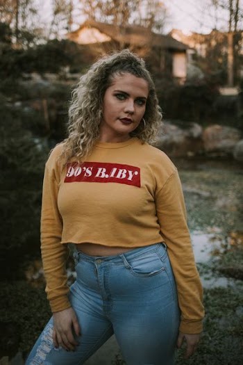 woman wearing brown sweatshirt standing near plants