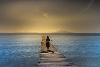 Woman Wearing Bucket Hat Walking On Brown Wooden Boardwalk