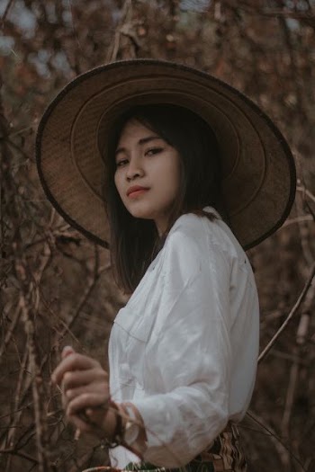 woman wearing conical hat surrounded by trees