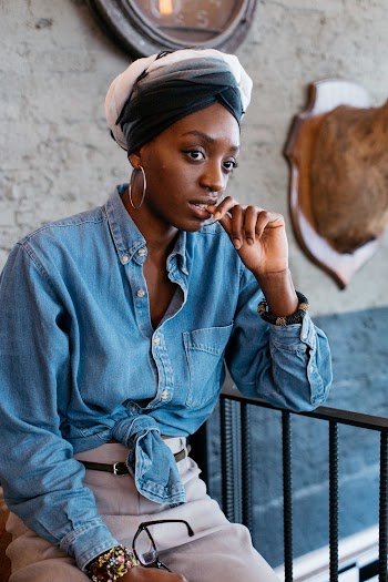 Woman Wearing Denim Jacket Sitting Beside Metal Railings