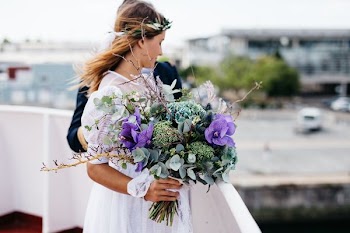 woman wearing dress holding flower bouquet beside man holding her waist