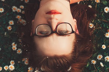 Woman Wearing Eyeglasses Lying On Grass