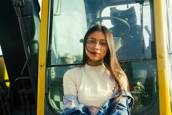 Woman wearing Eyeglasses Standing in front of Excavator