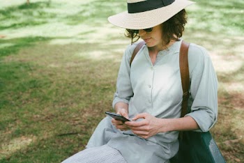 Woman Wearing Fedora Hat Sitting On Grass