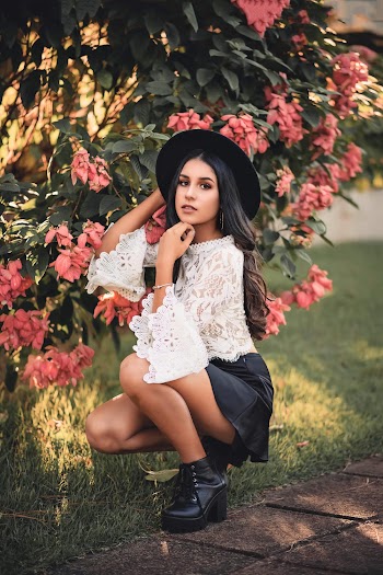 Woman Wearing Floral Blouse and Black Leather Miniskirt Squatting Beside of Pink Flowers