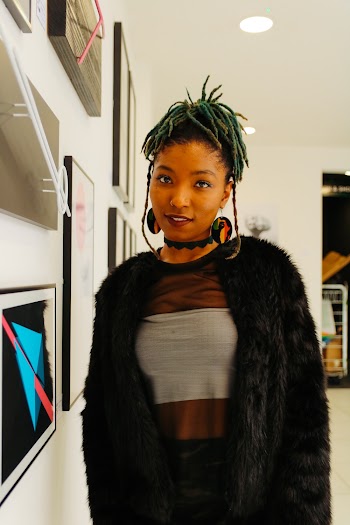 Woman Wearing Fur Coat Standing by the Paintings on Wall