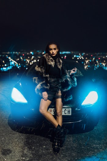 Woman Wearing Fur Jacket Leaning on Car's Hood