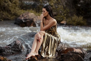Woman Wearing Gold Silk Tube Dress Sitting Beside River