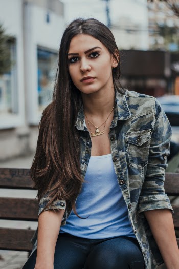 Woman Wearing Gray and Blue Jacket Sitting on Brown Wooden Bench