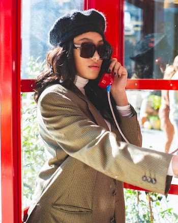 Woman Wearing Gray Coat Standing inside Telephone Booth