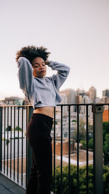 Woman Wearing Gray Crop Top and Black Pants Posing with Her Hands on Her Hair