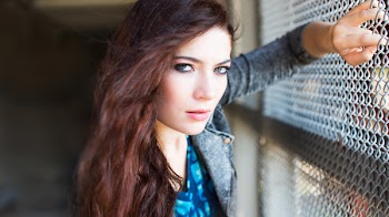 Woman Wearing Gray Denim Jacket Leaning on Gray Chain Link Fence at Daytime
