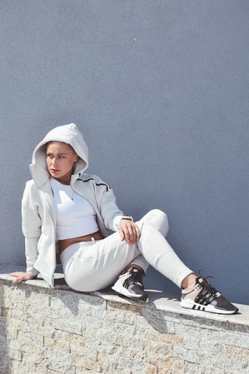 Woman Wearing Gray Full-zip Hoodie While Sitting on Gray Concrete Boulder