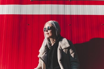 Woman Wearing Gray Jacket Against Red Background
