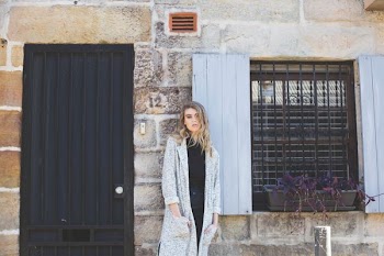 woman wearing gray robe standing near closed storm door